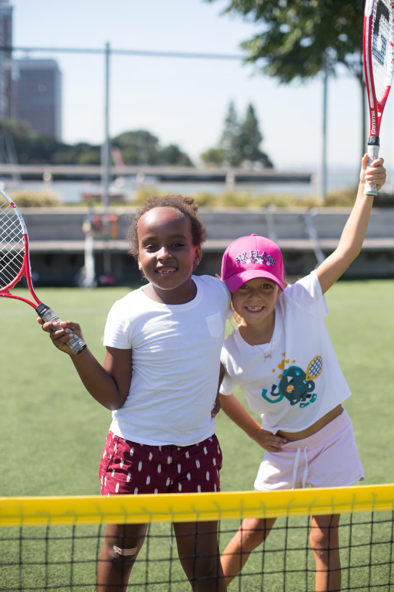 Two young tennis players smiling together at the net