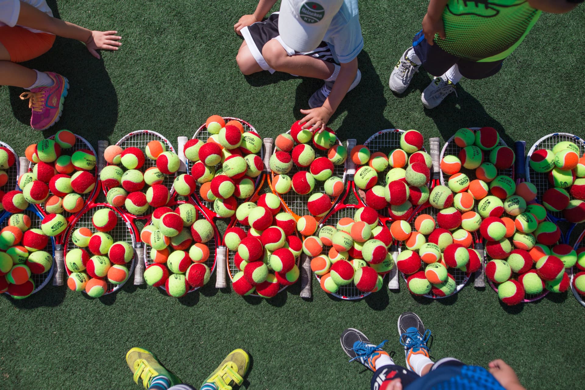 Kid-sized racquets and low-compression tennis balls on court
